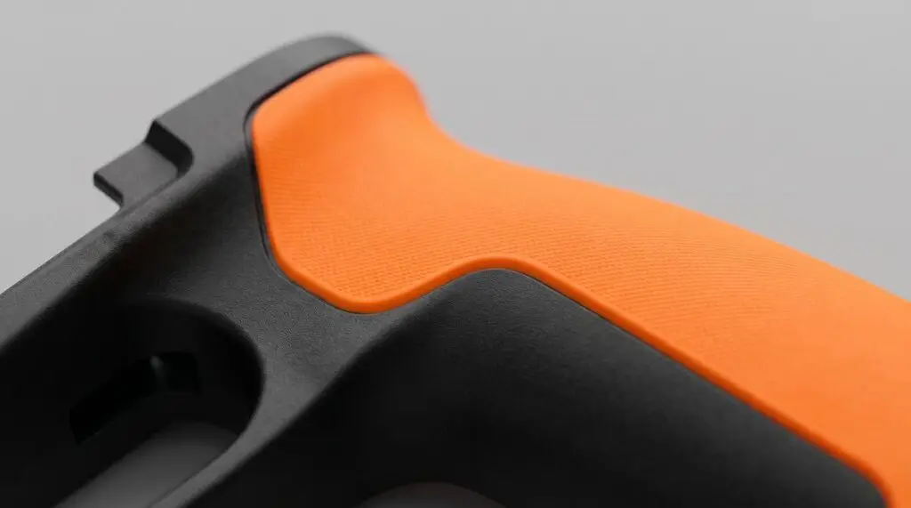 Close-up of an overmoulded part showing a rigid black plastic body with a soft-touch rubber grip moulded over it